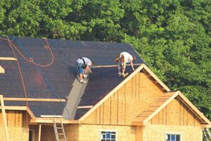 Homeowner examining roof shingles and attic insulation while checking for signs of moisture damage.